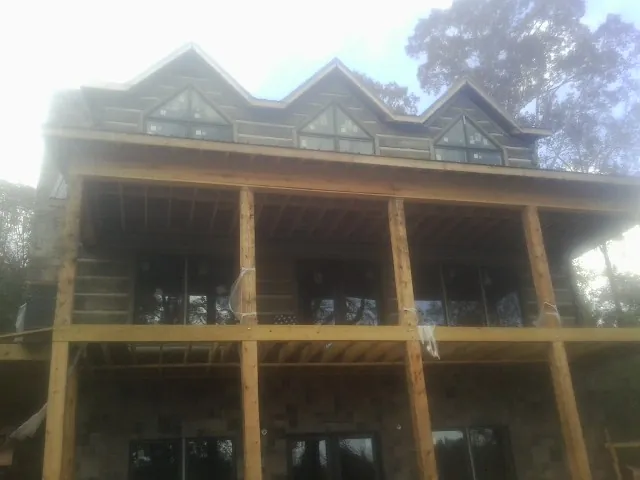 Dormers and porch framing on a large log home under construction — Roof Coating work by our crew in New Berlin